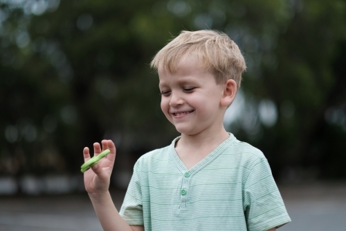 Young boy smiling playing with fidget spinner