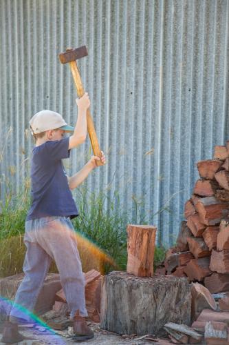 Young boy splitting wood for the fire - Australian Stock Image