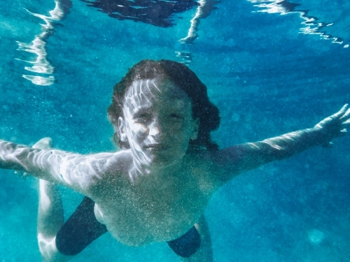 Young boy swimming underwater in blue ocean - Australian Stock Image