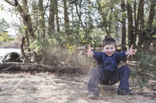 Young boy throwing sand in the air - Australian Stock Image