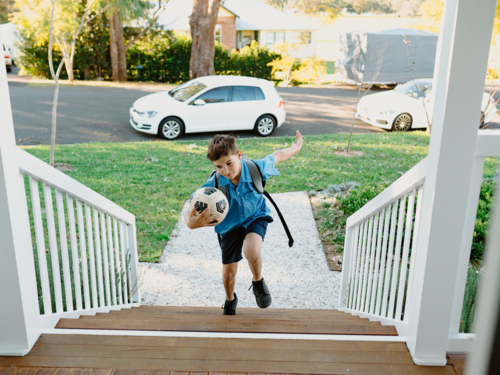 Young boy walking up the stairs with his soccer ball. - Australian Stock Image