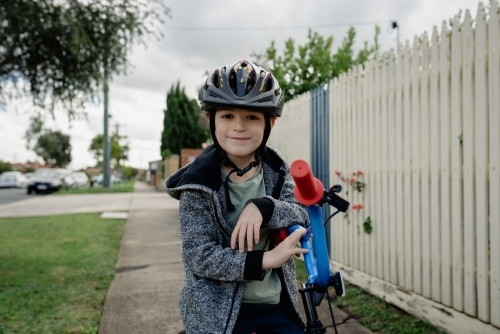 Young boy wearing bike helmet poses for a portrait on his bicycle; cycling around his neighbourhood