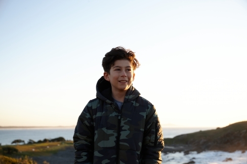Young boy wearing camo jacket on sunrise - Australian Stock Image