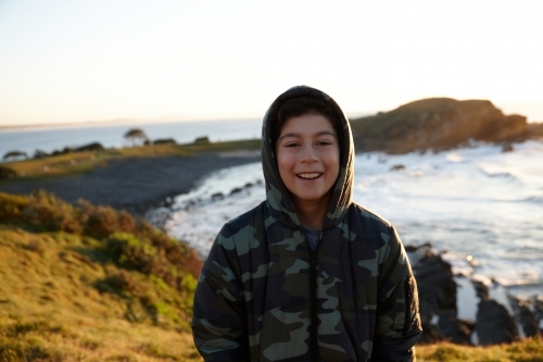 Young boy wearing camo jacket on sunrise - Australian Stock Image