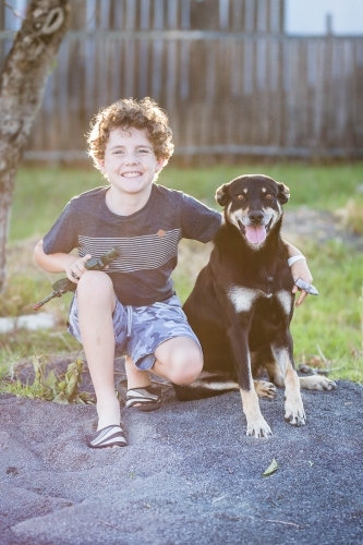 Young boy with arm around black and tan kelpie dog - Australian Stock Image