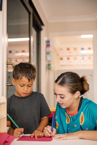 Young boy writing with carer - Australian Stock Image