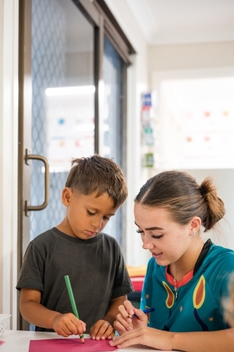 Young boy writing with carer - Australian Stock Image