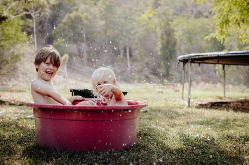 Young boys playing in a tub of water outside on a hot day