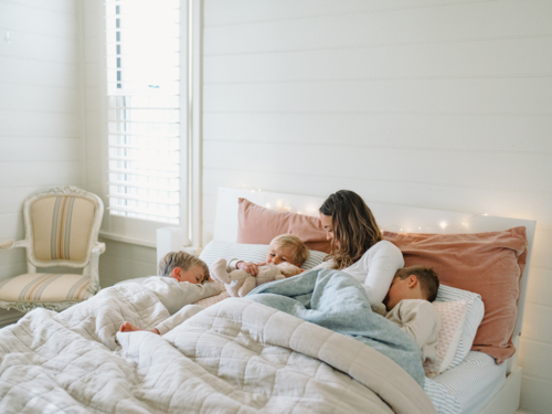 Young boys snuggling with mum on the bed - Australian Stock Image