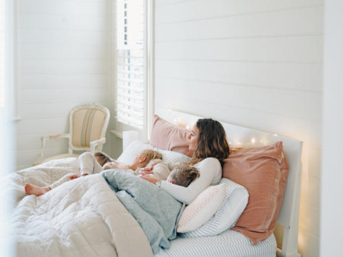 Young boys snuggling with mum on the bed - Australian Stock Image