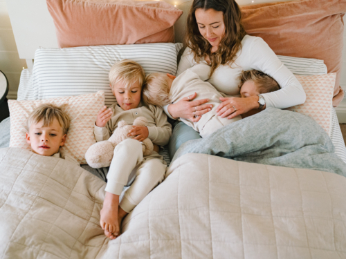 Young boys snuggling with mum on the bed - Australian Stock Image