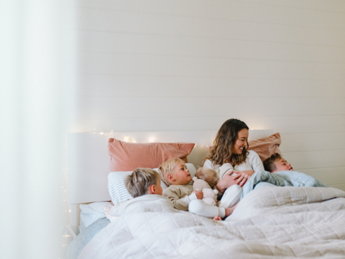 Young boys snuggling with mum on the bed - Australian Stock Image