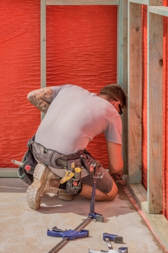 Young builder using tape measure on residential construction site - Australian Stock Image