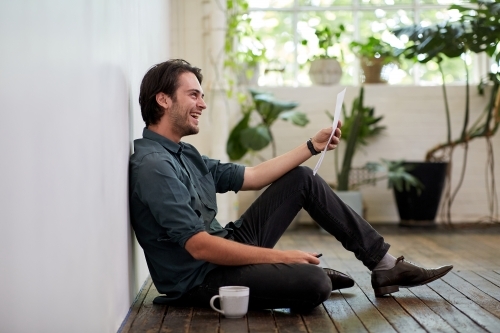 Young business man relaxing sitting on a timber floor in studio - Australian Stock Image