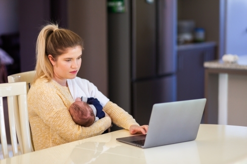Young businesswoman mum working from home on laptop with newborn baby