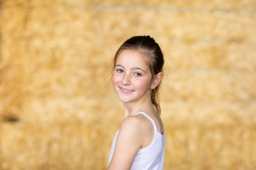 young caucasian girl with hair tied back wearing white singlet