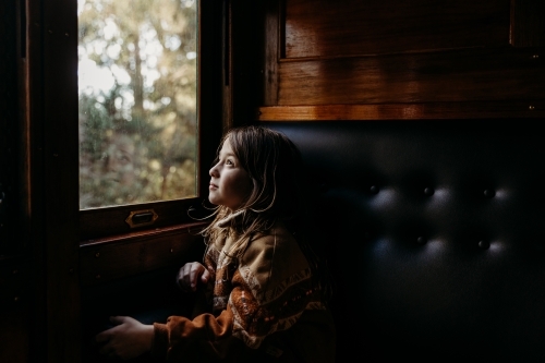 Young child looking out of window on dark train - Australian Stock Image