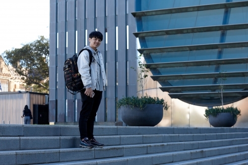 Young Chinese student standing on stairs at university campus - Australian Stock Image