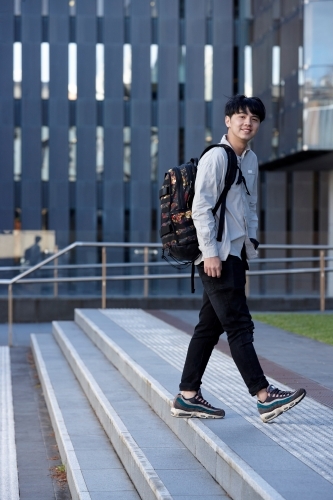 Young Chinese student walking on stairs at university campus - Australian Stock Image