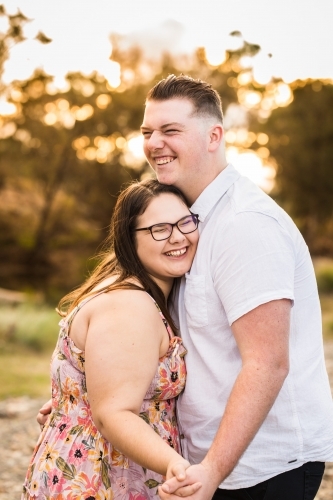 Young couple holding hands cuddling and laughing - Australian Stock Image