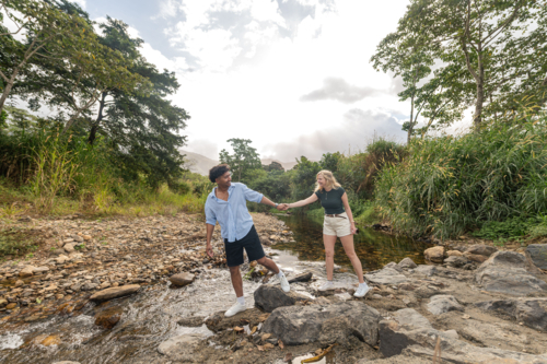 Young couple holding hands exploring a creek in far north Queensland - Australian Stock Image