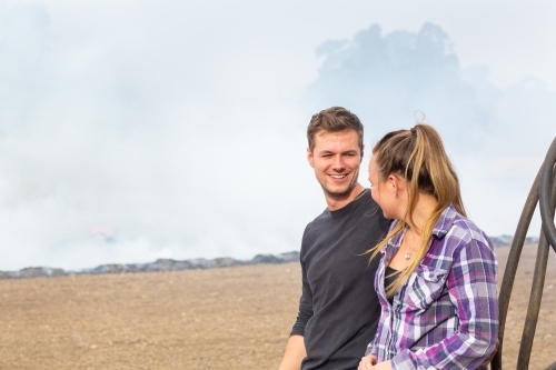 Young couple looking at each other outdoors with smoky background - Australian Stock Image