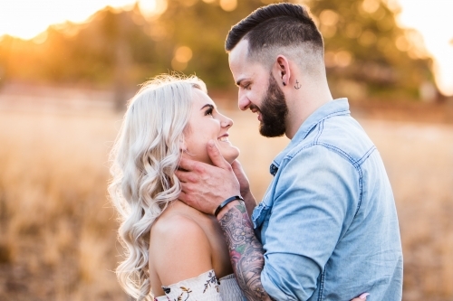 Young couple looking at each other smiling man holding woman's face - Australian Stock Image