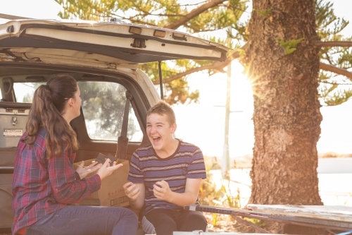 Young couple sitting on tailgate of 4WD vehicle