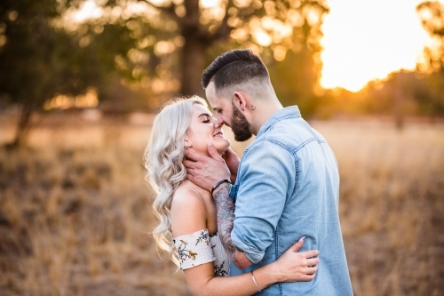 Young couple standing arm in arm faces close about to kiss - Australian Stock Image