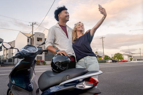 Young couple taking a selfie next to their motorbike at sunset - Australian Stock Image