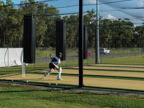 Young cricket batter practising running drills inside training nets - Australian Stock Image