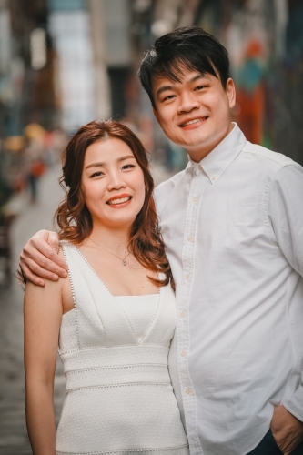 Young engaged couple posing together in Hosier Lane, iconic graffiti laneway in Melbourne - Australian Stock Image