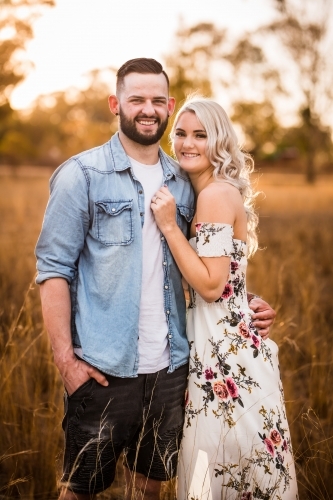 Young engaged couple standing with arms around each other smiling