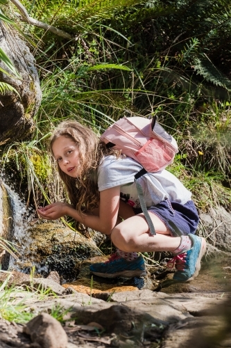 Young explorer drinking fresh water from the waterfall. - Australian Stock Image