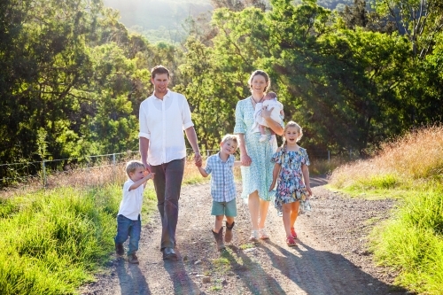 Young family walking down their driveway on a farm - Australian Stock Image