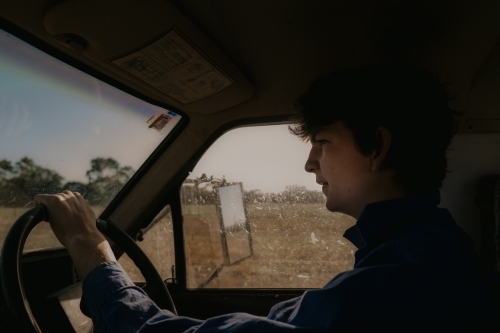 Young Farmer driving the ute through the paddocks in Summer