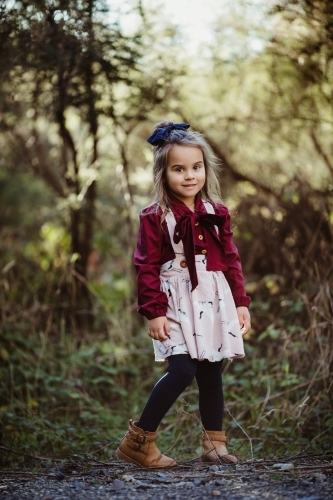 Young fashionable girl standing in bush setting smiling at camera - Australian Stock Image
