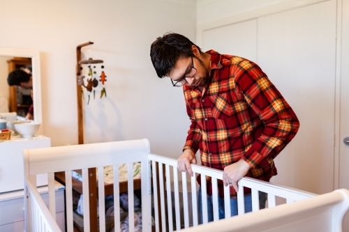 Young father in baby's nursery assembling cot