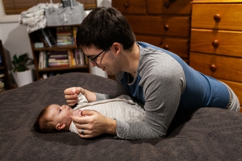 Young father playing with baby before bed in bedroom