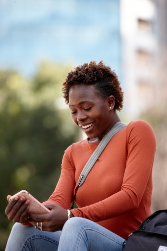 Young female photographer checking mobile phone messages in city