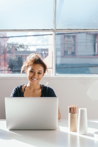 Young female working on a laptop with clear space for text - Australian Stock Image