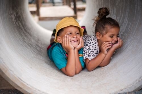 Young First Nations girl and boy playing together in a tunnel - Australian Stock Image