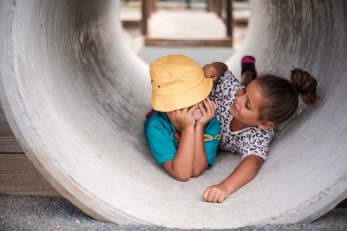 Young First Nations girl and boy playing together in a tunnel - Australian Stock Image