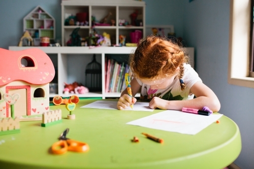 Young girl drawing at a table in a bedroom - Australian Stock Image