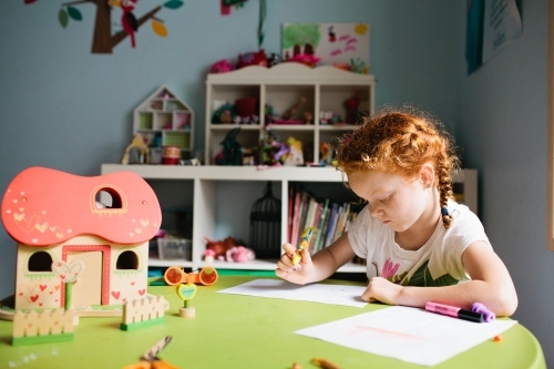 Young girl drawing at a table in a bedroom - Australian Stock Image