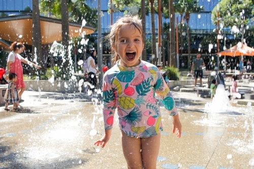 Young girl happily playing in an outdoor water park - Australian Stock Image