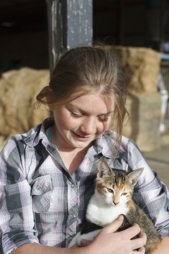 Young girl holding a farm cat