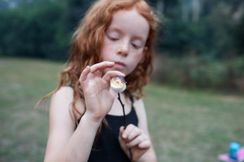 Young girl holding a marshmallow on a stick - Australian Stock Image