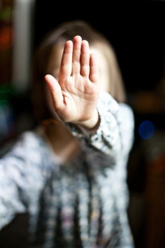 Young girl holding her hand up to the camera to say stop