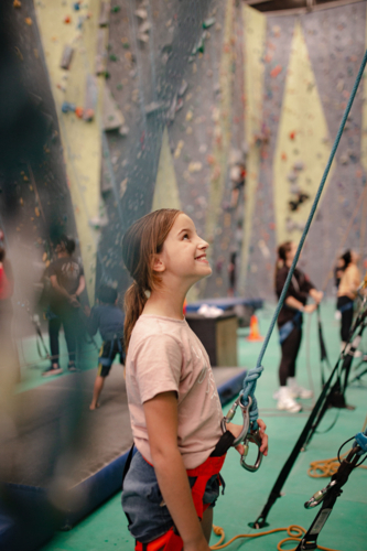 Young girl holding rope for rock climbing while looking up - Australian Stock Image